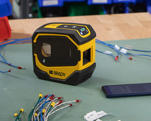 Az M511 nyomtató felcímkézett vezetékekkel és egy mobiltelefonnal.