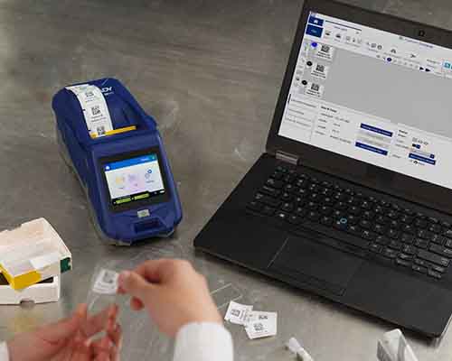 Egy személy, aki az M611-gyel nyomtatott címkét helyez egy mikroszkóp tárgylemezre a laborban.